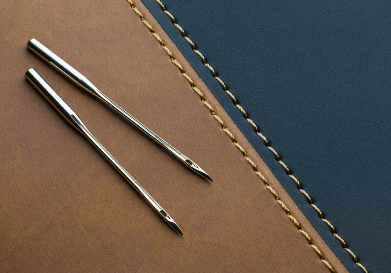 Needles placed on aleather material with stitches