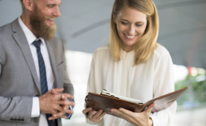 Acme Preston - Custom styles to help firm stand out Woman happily checking notes on her noteboo with a colleague