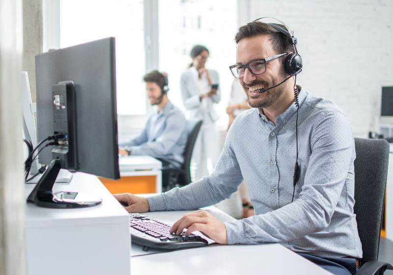 Smiling customer support operator with hands-free headset working in the office
